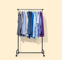 Mobile rack with shirts isolated on light yellow background. File contains a path to isolation.