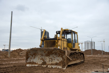 Bulldozer during land clearing and foundation digging at large construction site.  Crawler tractor with bucket for pool excavation and utility trenching. Dozer, Earth-moving equipment