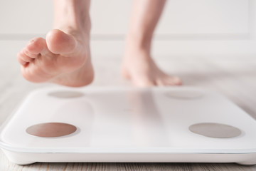 Female foot takes a step on smart scales that makes bioelectric impedance analysis, BIA, measurements of body fat. - obrazy, fototapety, plakaty