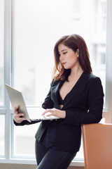 Portrait of Modern Beautiful Asian Business Woman in Attractive Casual Black Suit Holding Laptop Compute