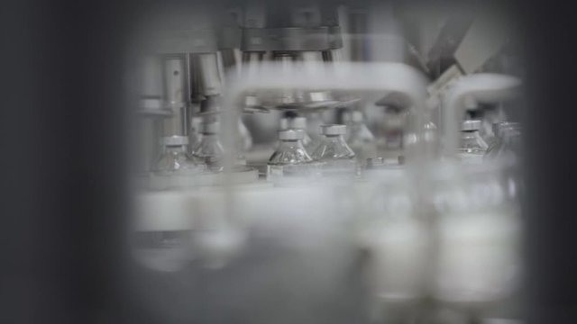 glass bottles filled and sealed with rubber and aluminum caps on medical solution conveyor line close up selective focus medical industry