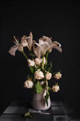 White lilies and roses against dark background