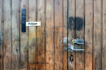 Großer Bildauschnitt einer braunen Holz Türe mit Sicherheits Einrichtungen, Klinke Schloß und Riegel. stark gealtert. Nürtingen, Deutschland