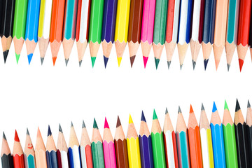 Different rows of different color pencil crayons placed on a white background