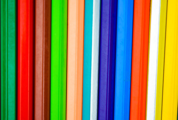 One row of different color pencil crayons placed on a white background