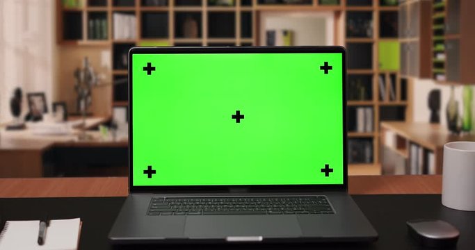 Zoom in on laptop computer with Green screen Mock-up on wirking desk in office