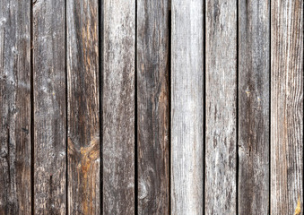 The texture of the gray wooden surface of the fence, wall, floor with vertically spread boards close-up.