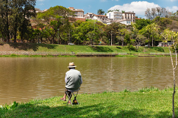 Man sitting in chair fishing on Lake Taboao, in the city of Bragança Paulista, Brazil, a tourist town known in the inland of Sao Paulo