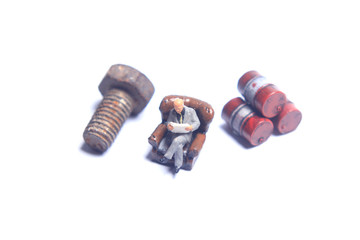 Photo Close Up, Scale HO Business Man Toy, Reading Business Report Beyond Red dirty Oil Barrel and dirty screw, at White Background, for your element design oil or fuel related