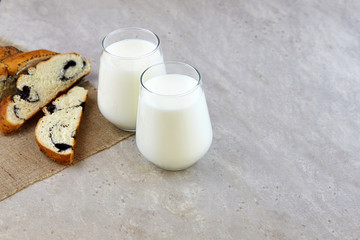 Organic probiotic kefir or yogurt with probiotics in glasses and a bun with poppy seeds on a light background. Homemade cold fermented milk drink.