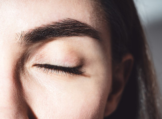 Beautiful female eye. One brown eye close-up. Closed eye. Mascara on the eyelashes. Eye and eyebrow near. Bare eye without makeup. For makeup.