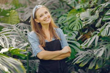 Woman in a greenhouse. Lady works with trees. Girl in a black apron.
