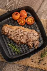 Juicy grilled steak medium rare beef on the grill pan with tomato and rosemary , wooden table - Stock photo