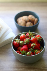 Bowl of chocolate chip cookies, bowl of strawberries and an open book on a table. Selective focus.