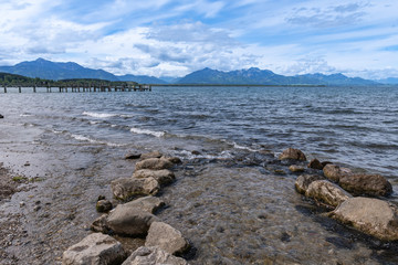Chiemsee Ufer im Frühjahr im Mai mit Mündendem Baach und Steinen,  Steg und Wellen