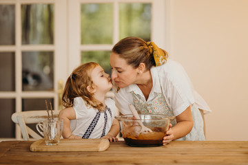 Fototapeta premium Loving beautiful mother and daughter cooking together a chocolate brownie and having fun