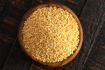 Bowl of Whole Millet in a Wood Bowl on a Rustic Dark Wood Table