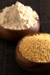 Bowls of Whole Millet and Millet Flour in Wood Bowls on a Dark Table