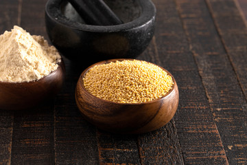 Bowls of Whole Millet and Millet Flour in Wood Bowls on a Dark Table