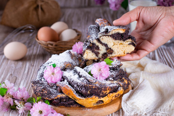 Homemade wicker cupcake with poppy seeds, flowers and icing sugar on a white wooden table. Delicious yeast pastries