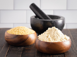 Bowls of Whole Millet and Millet Flour in Wood Bowls on a Dark Table