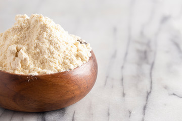 Bowl of Millet Flour in a Wood Bowl on a White Marble Countertop