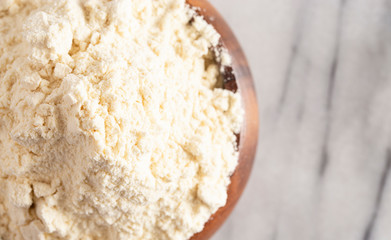 Bowl of Millet Flour in a Wood Bowl on a White Marble Countertop
