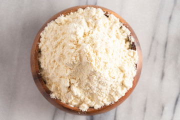 Bowl of Millet Flour in a Wood Bowl on a White Marble Countertop