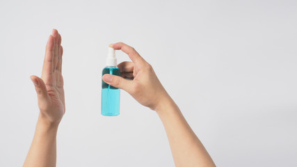 Right hand is holding Alcohol Spray and facing left hand on white background.