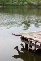 Guy is sitting near the lake on a wooden bridge