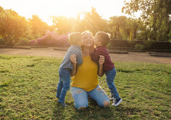 Twin brothers kissing her mother in a natural park - Young mother enjoy the day with her twoo sons - Family, mother and childs love concept