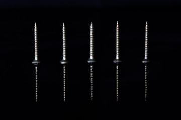Woodworking screws with a reflection in a black glass tile