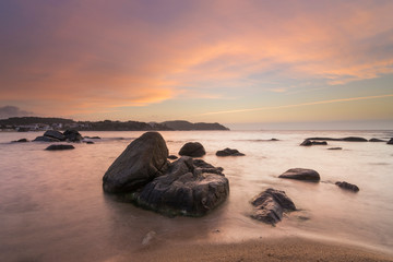 Fototapeta na wymiar Beach with rocks and pink clouds in the sky