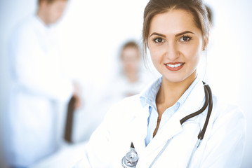 Female doctor smiling on the background with patient in the bed and two doctors