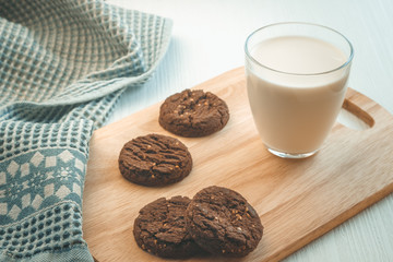glass of milk and chocolate cookies on a wooden background