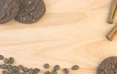 Chocolate cookies, coffee beans, cinnamon sticks  are on the wooden table.