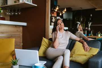 Obraz premium An attractive young caucasian woman with a phone in her hand sits in a cafe
