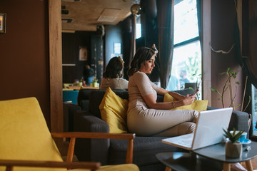 An attractive young caucasian woman with a phone in her hand sits in a cafe
