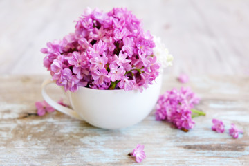 Obraz na płótnie Canvas Cup of tea with lilac flowers on wooden background. Spring time. Vase with lilac. Copy space for text. The concept of holidays and good morning wishes.