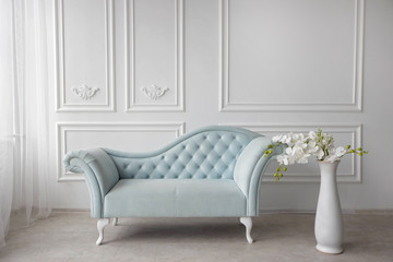 Baroque sofa. Vintage furniture. Pastel blue sofa with carriage tie. Restoration of vintage furniture. Furniture manufacturing. Interior design. A large white vase with orchids.