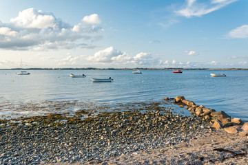 Scenic stony beach and rocks with boats in the background at the Baltic Sea in Northern Germany