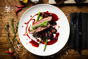 Duck breast with asparagus, salad and sauce on white plate. Delicious healthy grilled and roasted...