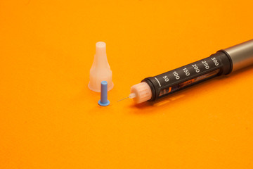 injector pen, insulin pen and insulin needle on orange background