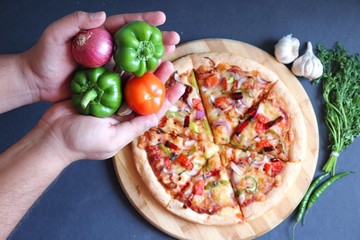 Food- Traditional Italian veggie pizza. Toppings are capsicum, corn, tomatoes, onion, red chilies and cheese. Ingredients and vegetables background with copy space.