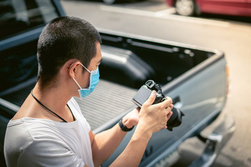 Asian man is wearing surgical mask while holding a camera during covid19 or corona virus spread