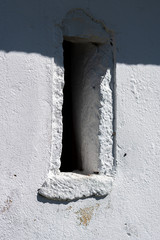 detail of a narrow window in a chapel painted white lime