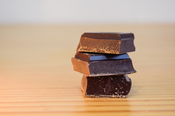 Onzas de chocolate negro sobre una mesa de madera con fondo claro desenfocado