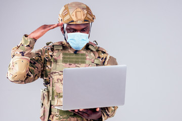 African American soldier smiles while typing a computer videocall with wife and child