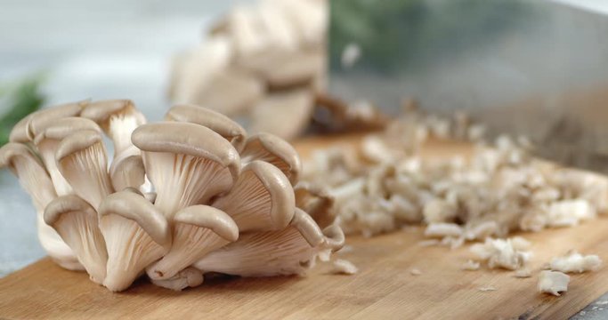 With a large knife cut a bunch of mushrooms into pieces.