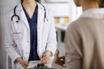 Doctor and patient discussing current health examination while sitting in clinic. Perfect medical...